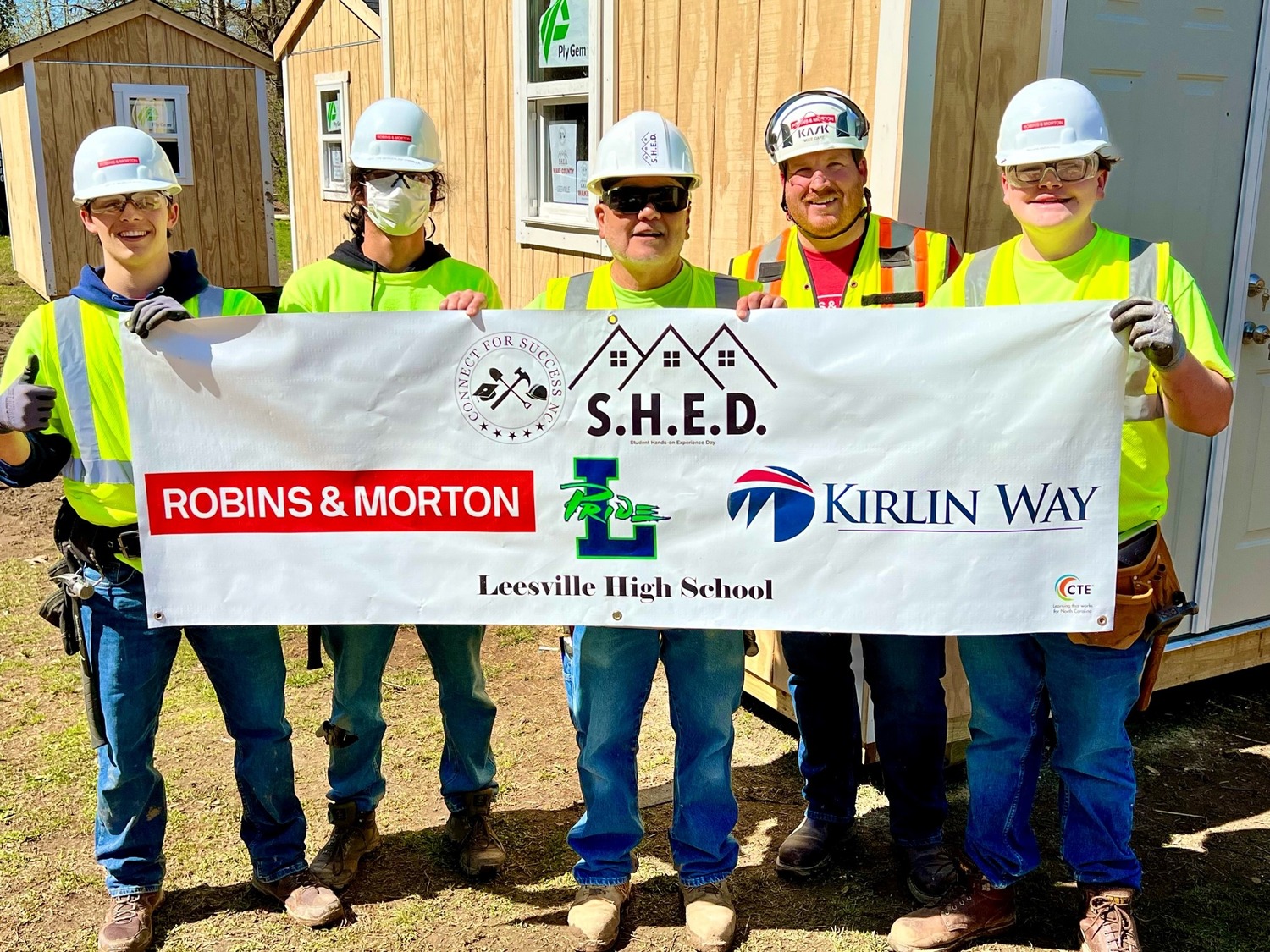construction team holding up a banner for the Build a SHED Competition