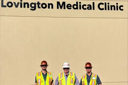three construction workers standing in front of a hospital