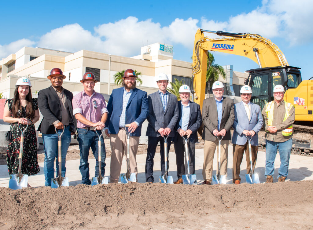 people posing in hard hats with shovels