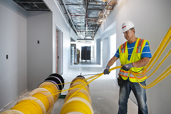 Construction worker pulling fiber optic cable